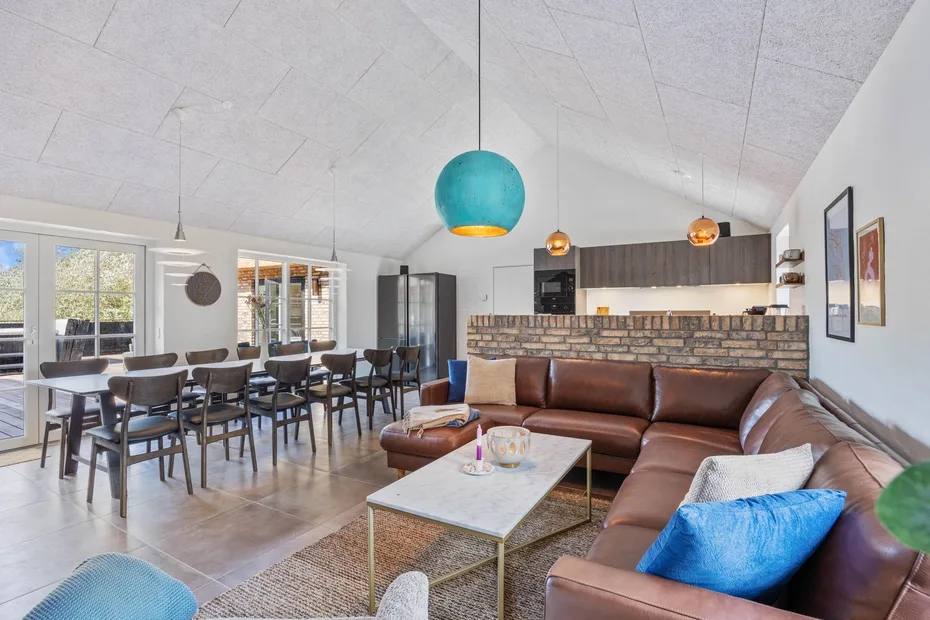 An open-plan living and dining area with a brown sectional and long dining table.