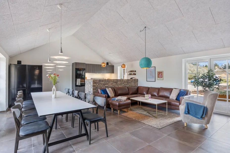 An open-plan living and dining area features a sectional sofa and a long dining table.