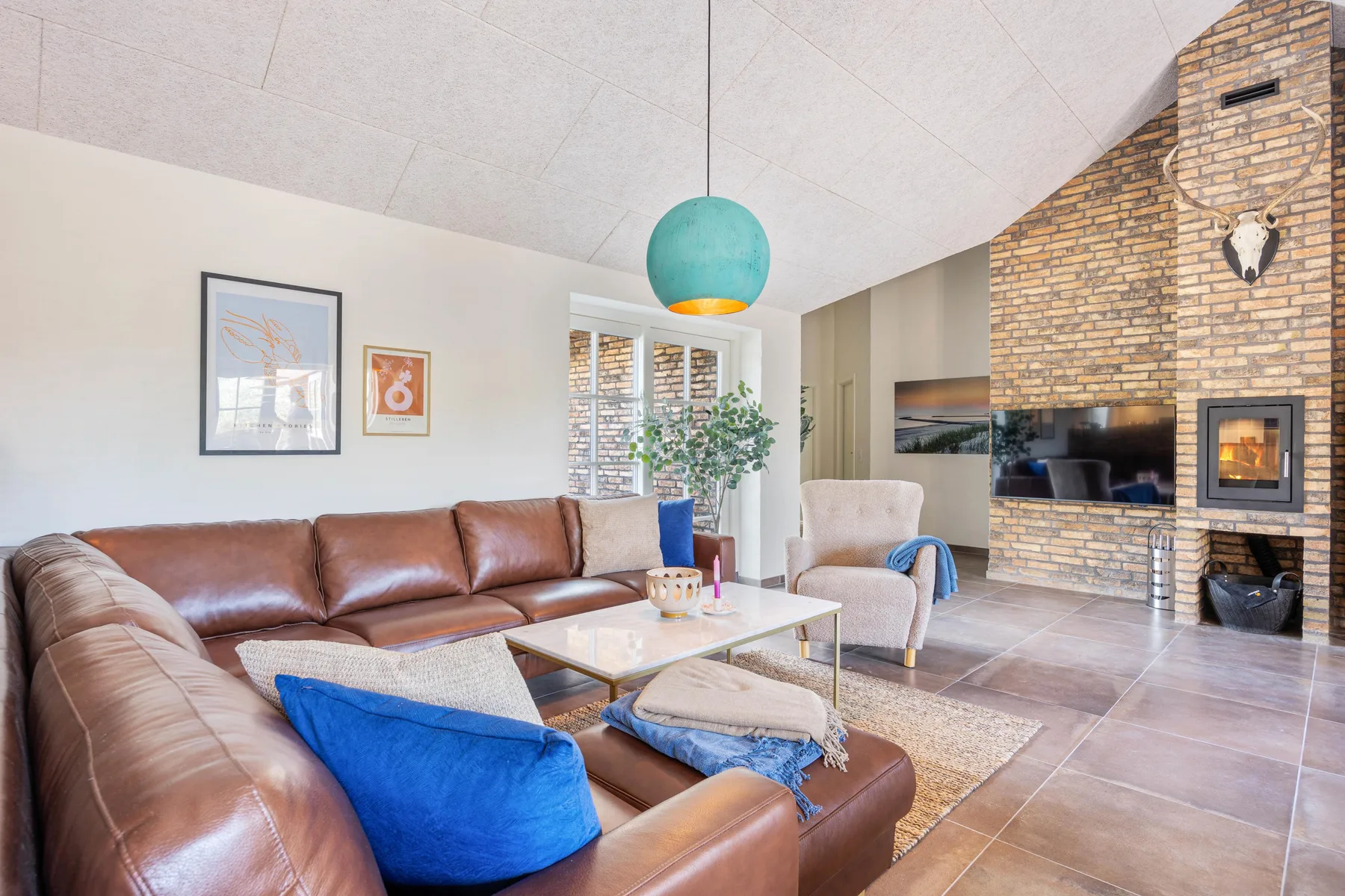 A living room with brown seating, a coffee table, and a brick fireplace.