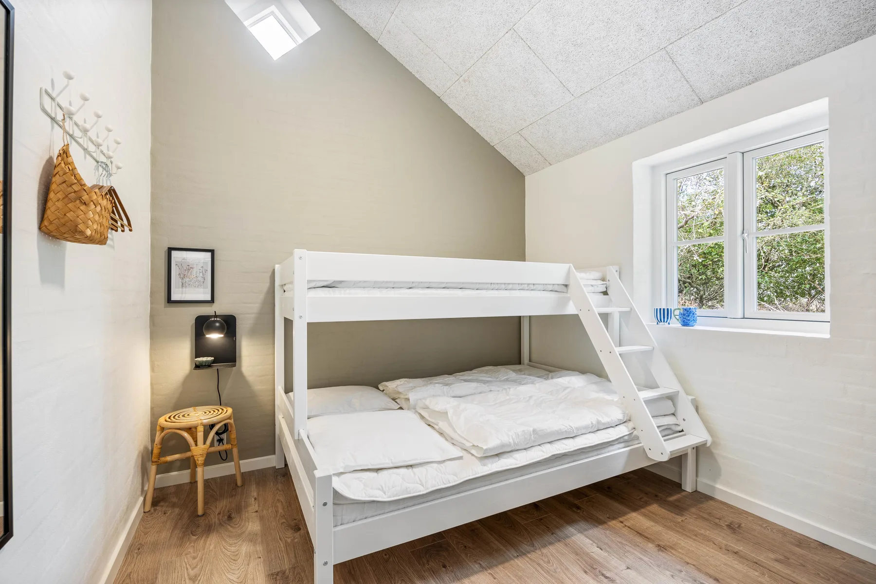 A bright bedroom with a white bunk bed and a large window.