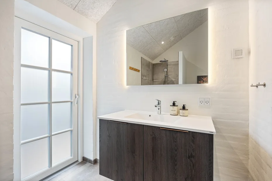 A bright bathroom with a wide vanity beneath a large mirror.