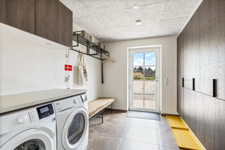 A laundry room with washing machines, built-in cabinets, and a glass door.