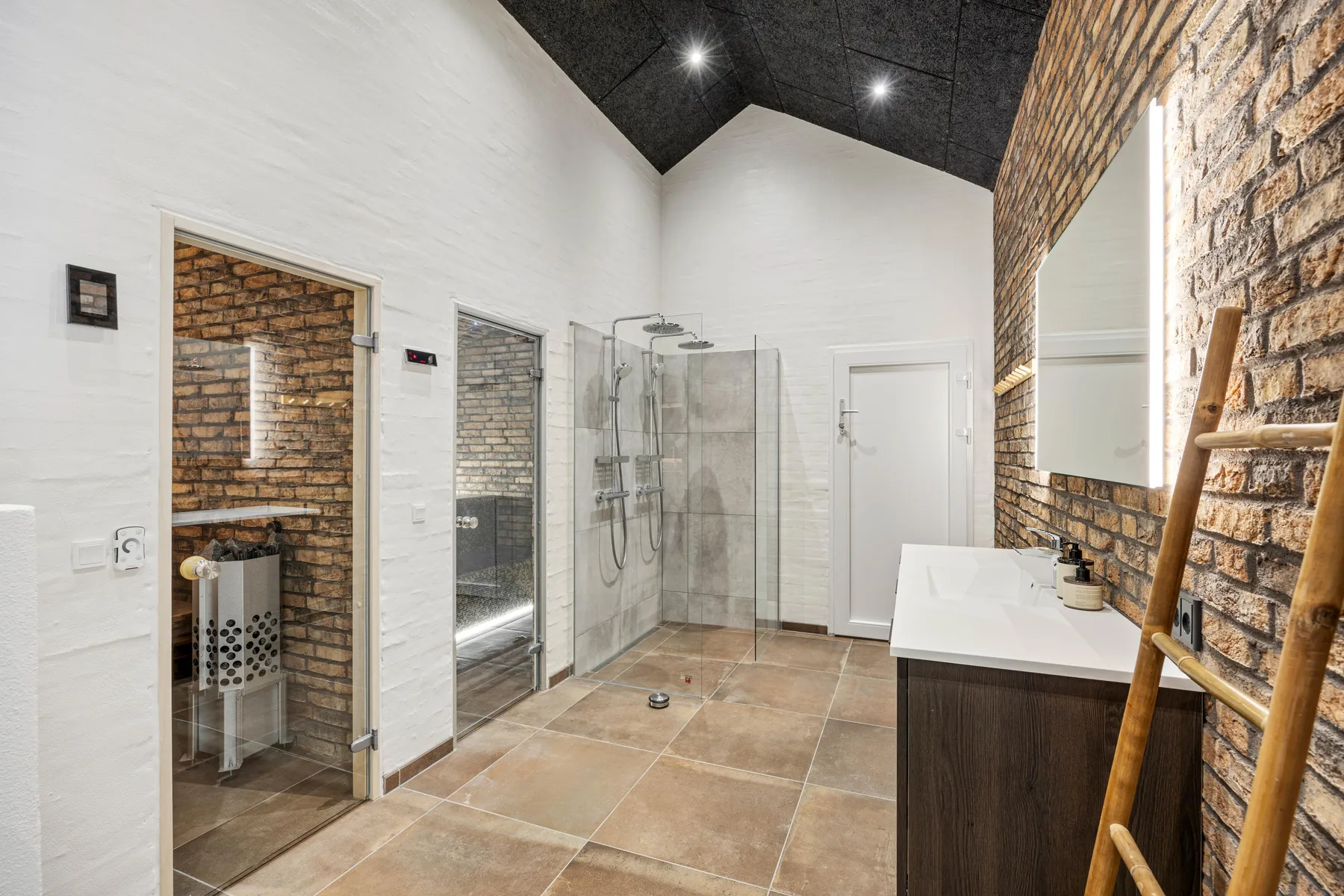 A spacious bathroom with a glass shower and a white sink.