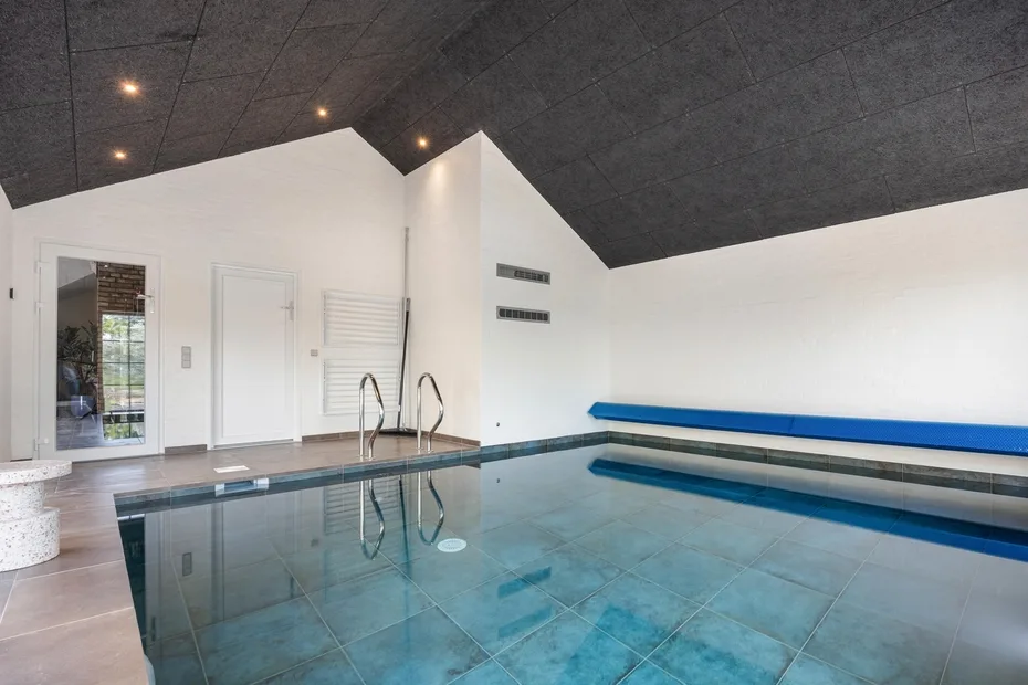 An indoor swimming pool with blue water and a metal ladder.