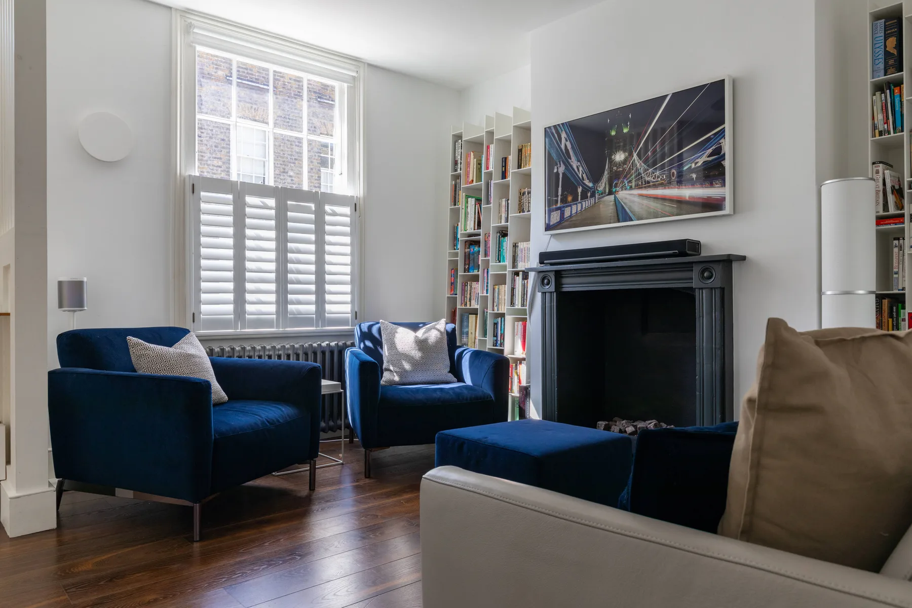 A living room with blue seating, bookshelves, and a fireplace.