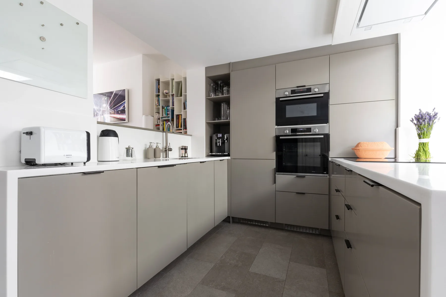 A modern kitchen with built-in appliances and gray cabinetry.