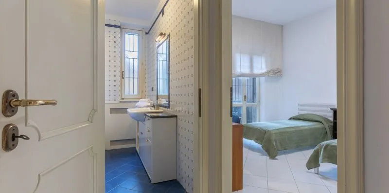 Una puerta abierta muestra un baño junto a un dormitorio con una cama.
