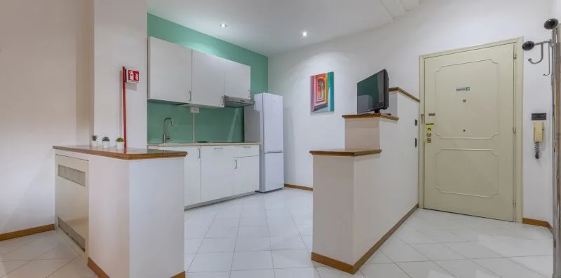 A compact kitchen area with white cabinets and a refrigerator.