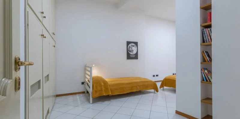 Un dormitorio con dos camas cubiertas con ropa de cama dorada y una estantería empotrada.