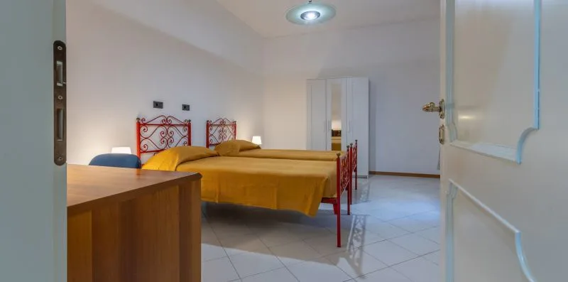 Un dormitorio con una cama doble, mesitas de noche y suelo de baldosas.