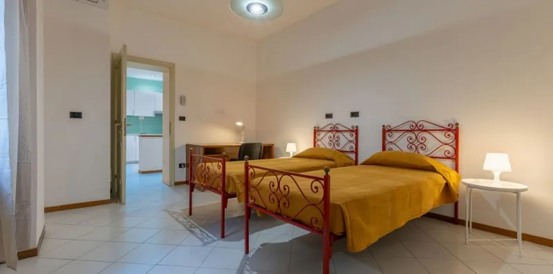 Un dormitorio con dos camas cubiertas con ropa de cama amarilla y mesitas de noche.