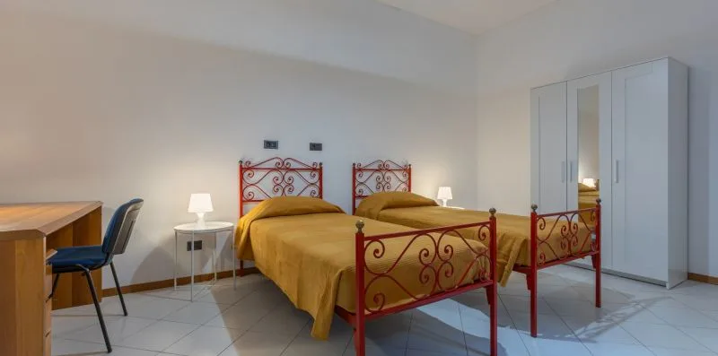 A bedroom with two beds and a tall wardrobe.