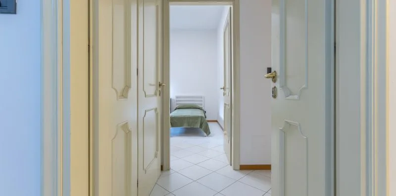 Un pasillo con puertas abiertas conduce a un dormitorio con una cama.