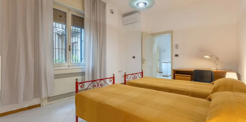 Un dormitorio con dos camas, una ventana y un escritorio.