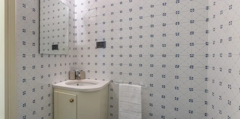 Un lavabo de baño con azulejos, un espejo y un lavamanos.