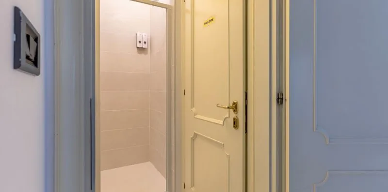 Una puerta da a un espacio interior con azulejos, junto a una puerta con paneles.