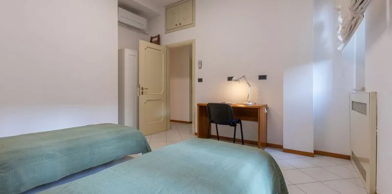 Un dormitorio con dos camas y un escritorio junto a la ventana.