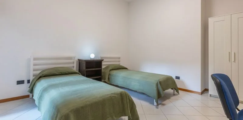 Un dormitorio con dos camas, una mesita de noche y un armario.