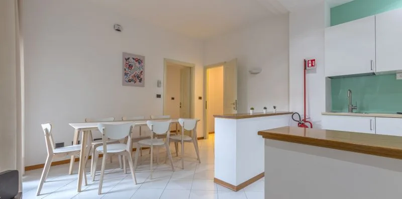 Un comedor con una mesa larga está junto a una barra de cocina.
