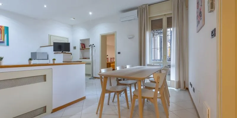 A bright dining area with a wooden table beside the kitchen counter.