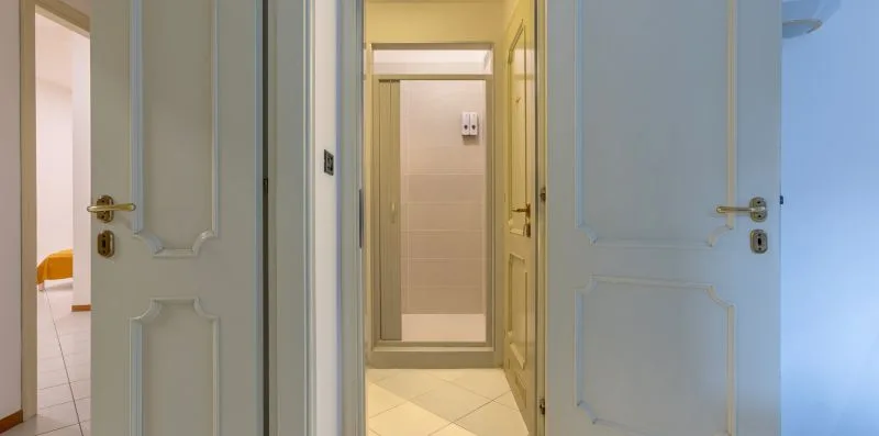 Un pasillo interior con puertas abiertas y suelo de baldosas.