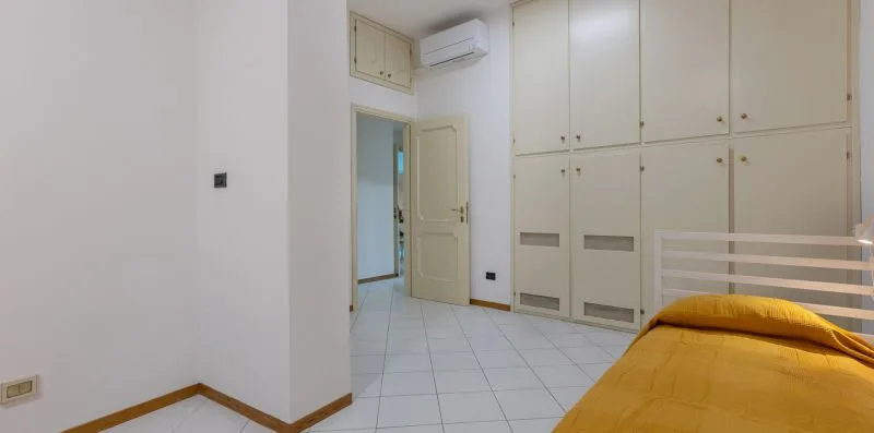 Un dormitorio con una cama amarilla junto a armarios empotrados y una puerta abierta.