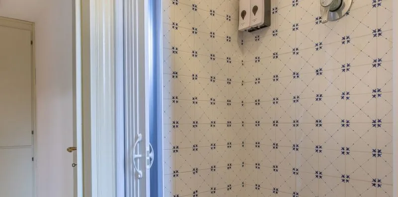 Una pared de baño con azulejos y un pequeño accesorio montado en la pared.