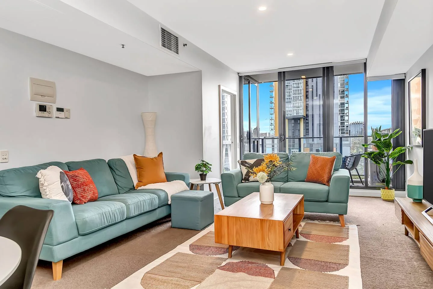 A bright living room with seating arranged around a coffee table and large windows.