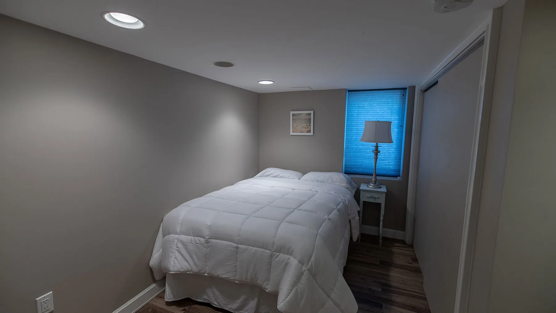 Un dormitorio con una cama vestida de blanco junto a una ventana.