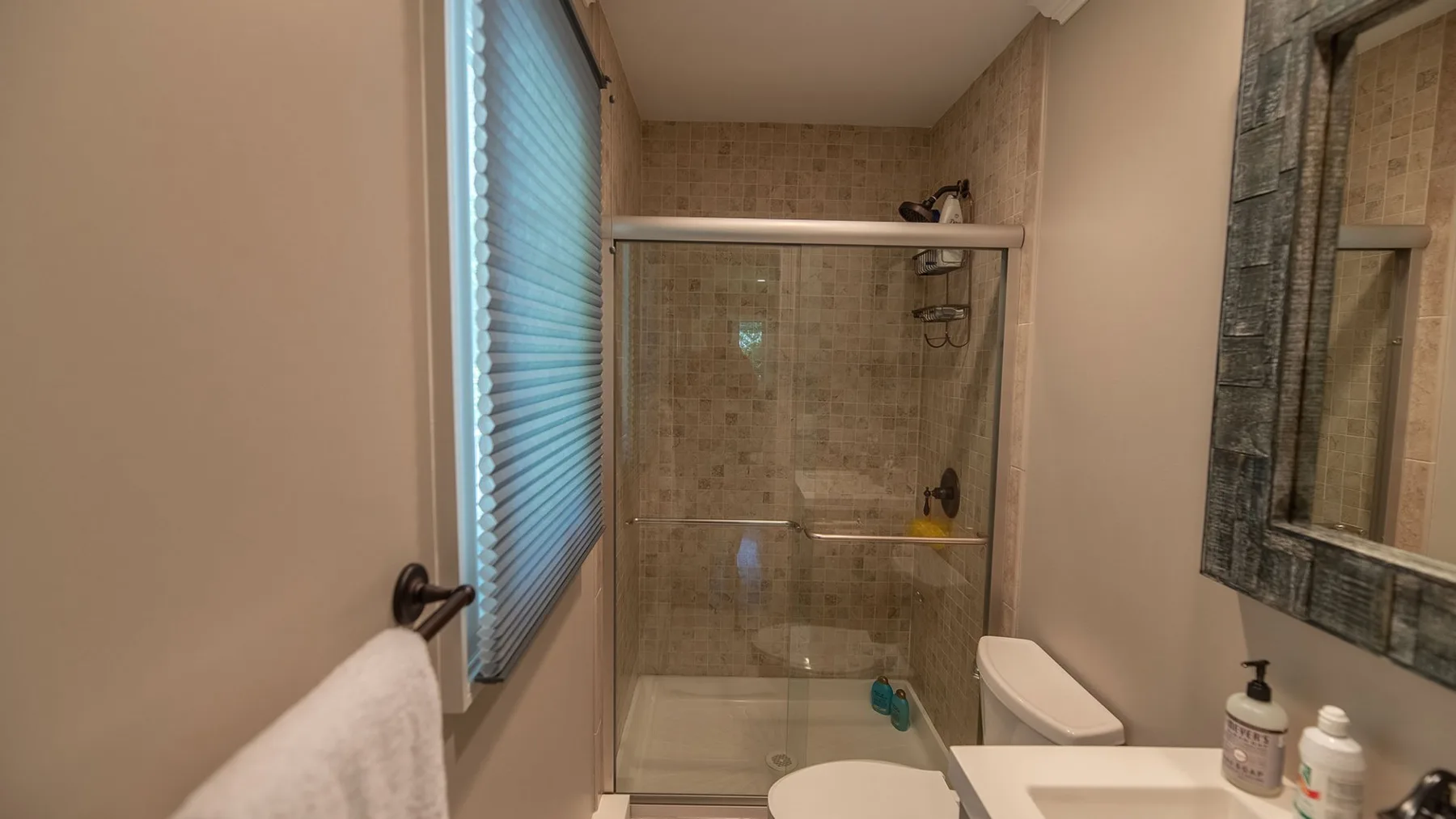 Un baño con ducha de vidrio, inodoro y ventana.