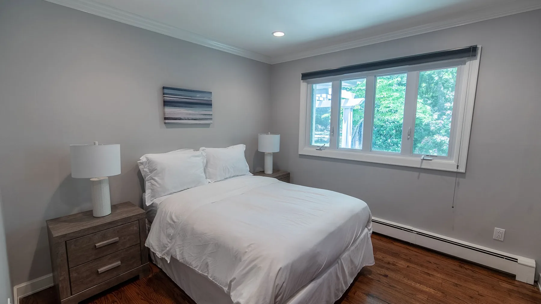 Un dormitorio con una cama bien tendida junto a una ventana grande.