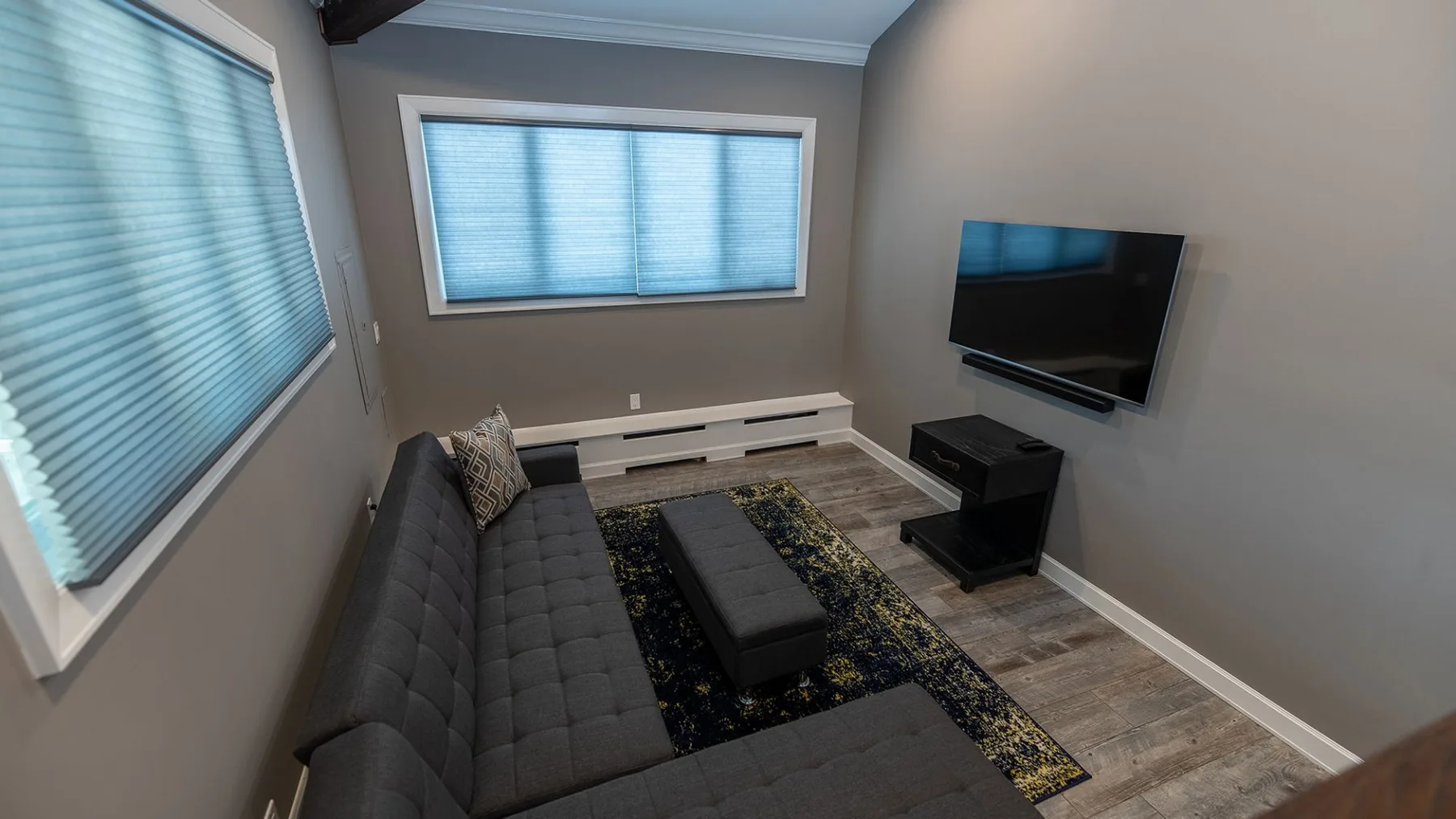 Una sala de estar con asientos, un televisor y ventanas con persianas.