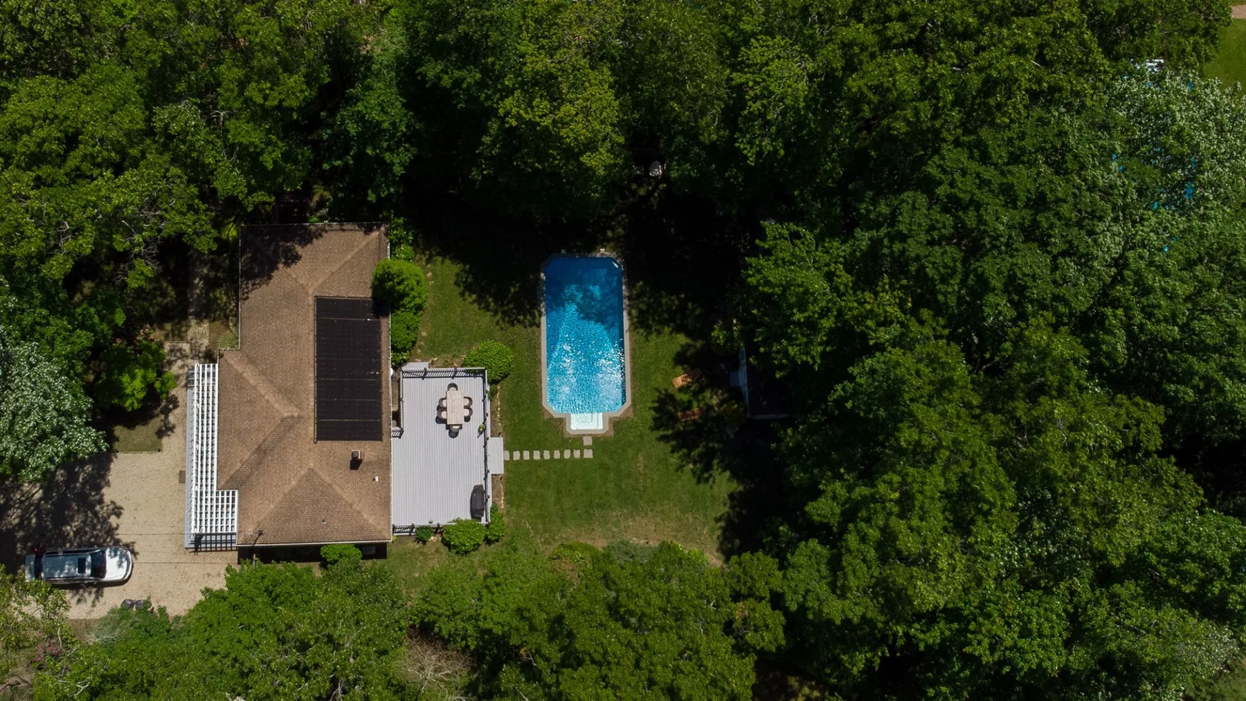 Una vista aérea muestra una casa, una piscina y árboles alrededor.
