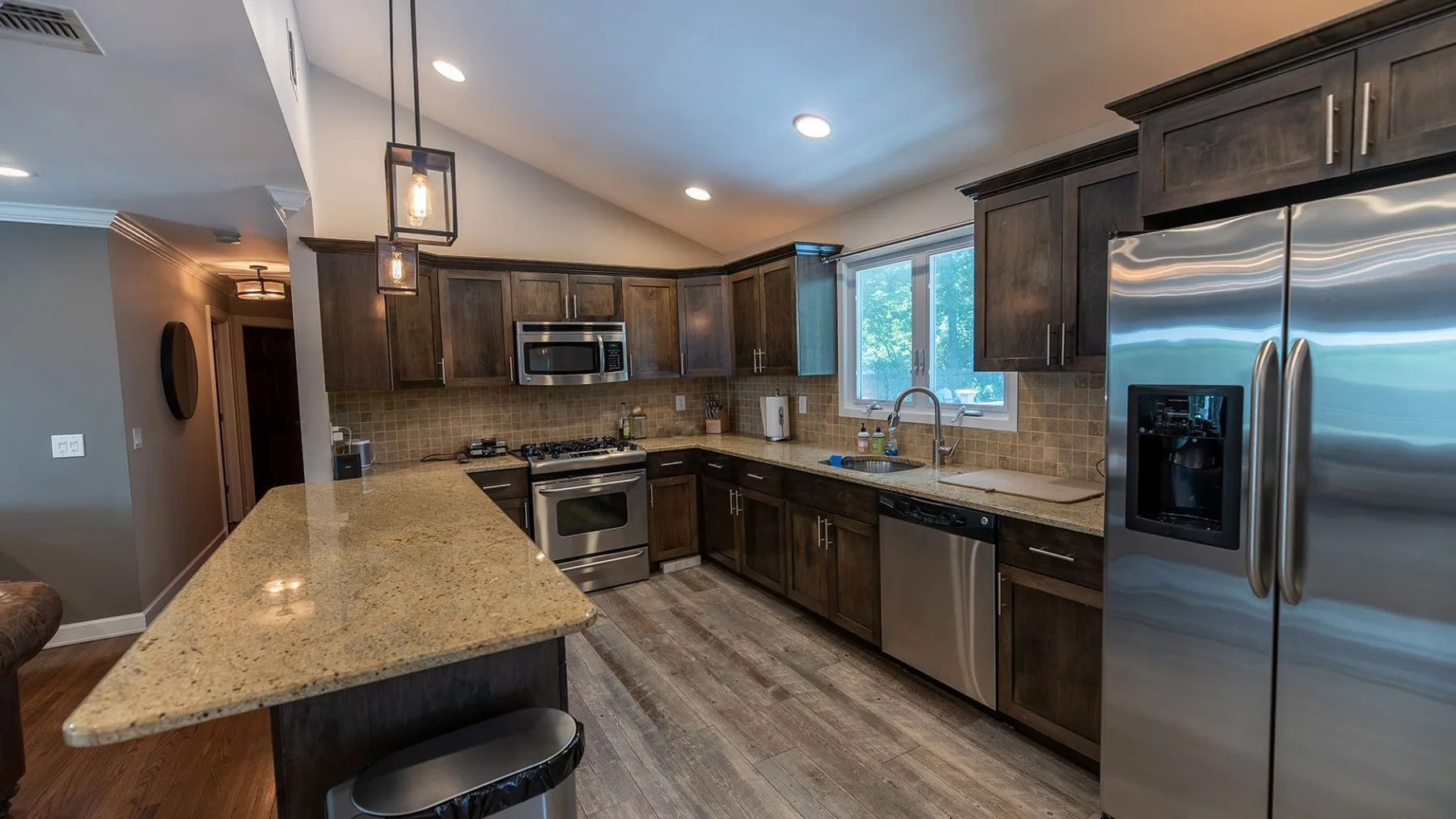 A kitchen with dark cabinets, stainless steel appliances, and a central island.
