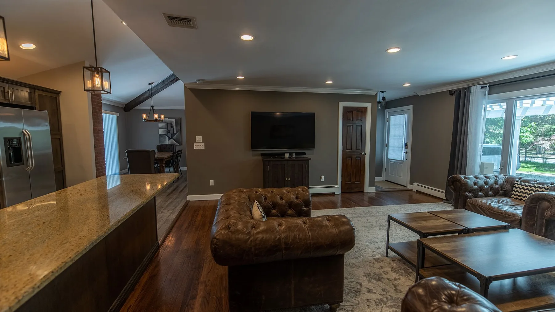 A living room with leather seating, a television, and a stone-topped counter.