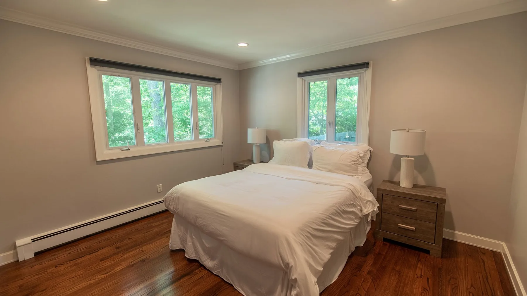 Un dormitorio con una cama entre dos ventanas.