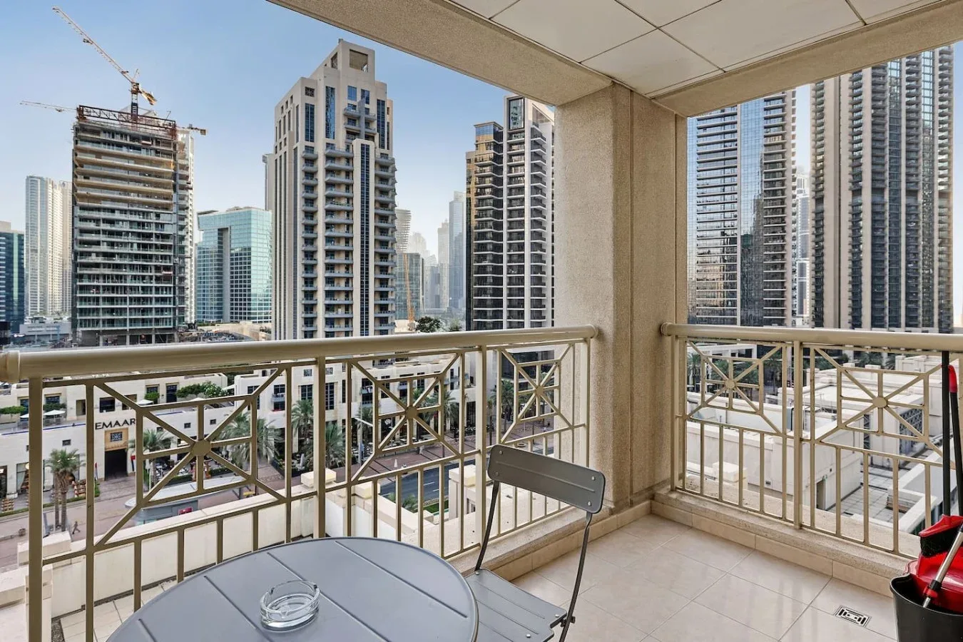 Un balcón con vistas a varios edificios altos, con una mesa pequeña y asientos.