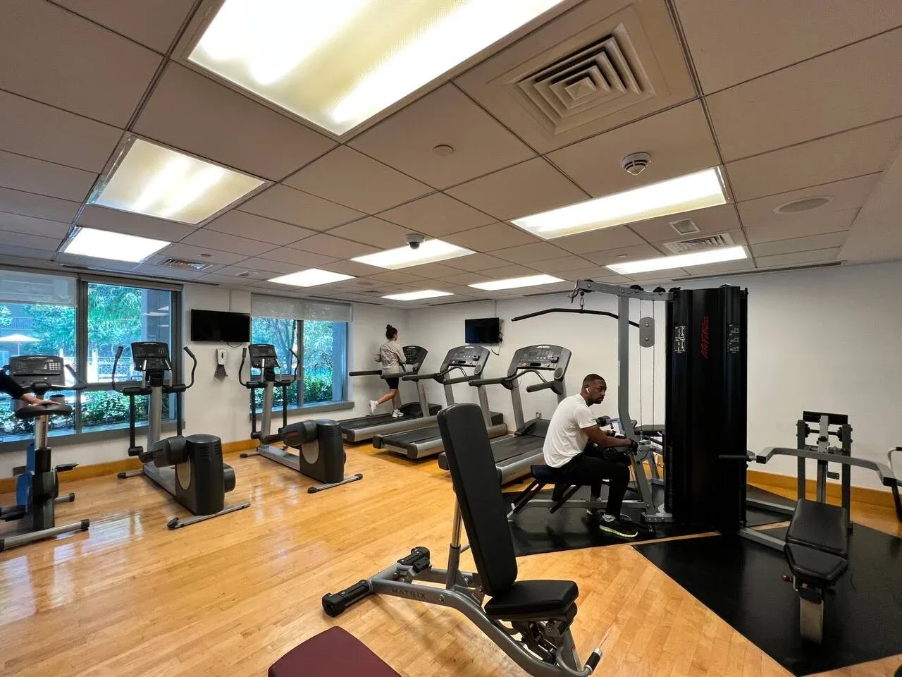 Un gimnasio con cintas de correr, bicicletas estáticas y equipo de pesas.