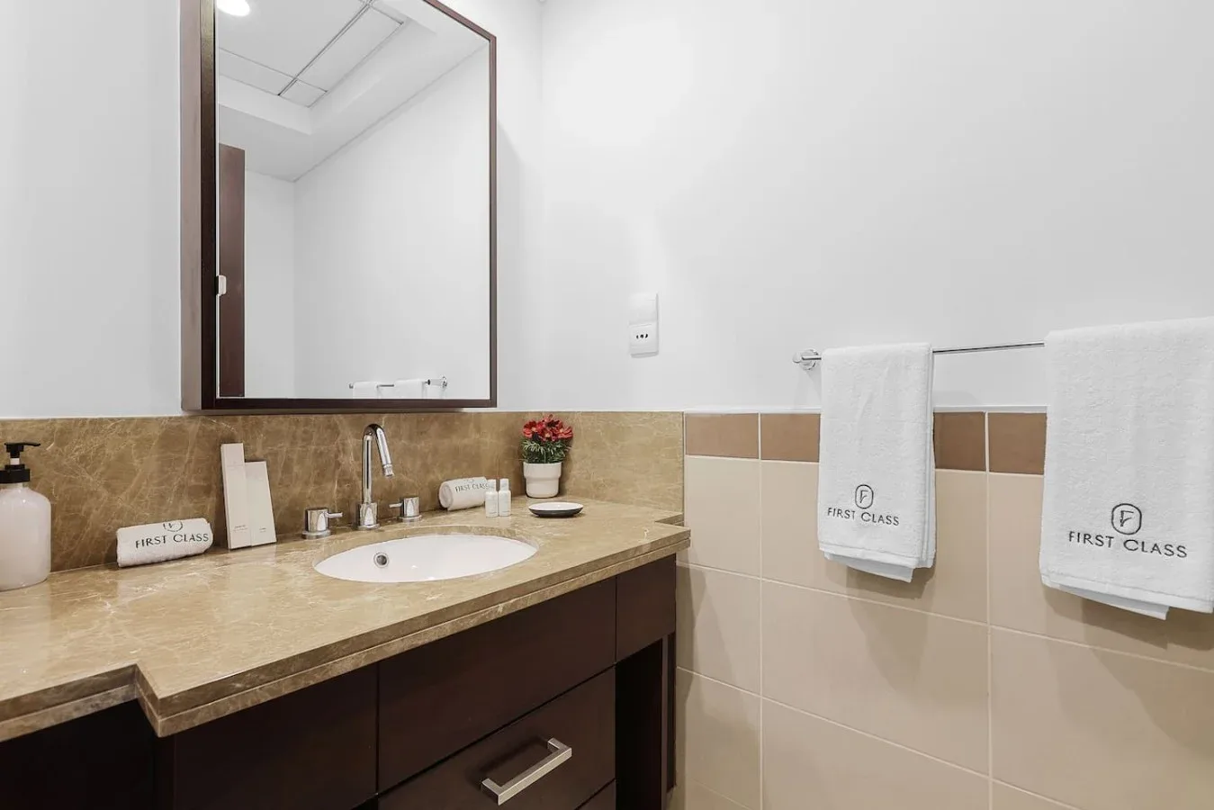 Un lavabo de baño con espejo y toallas colgadas en la pared.