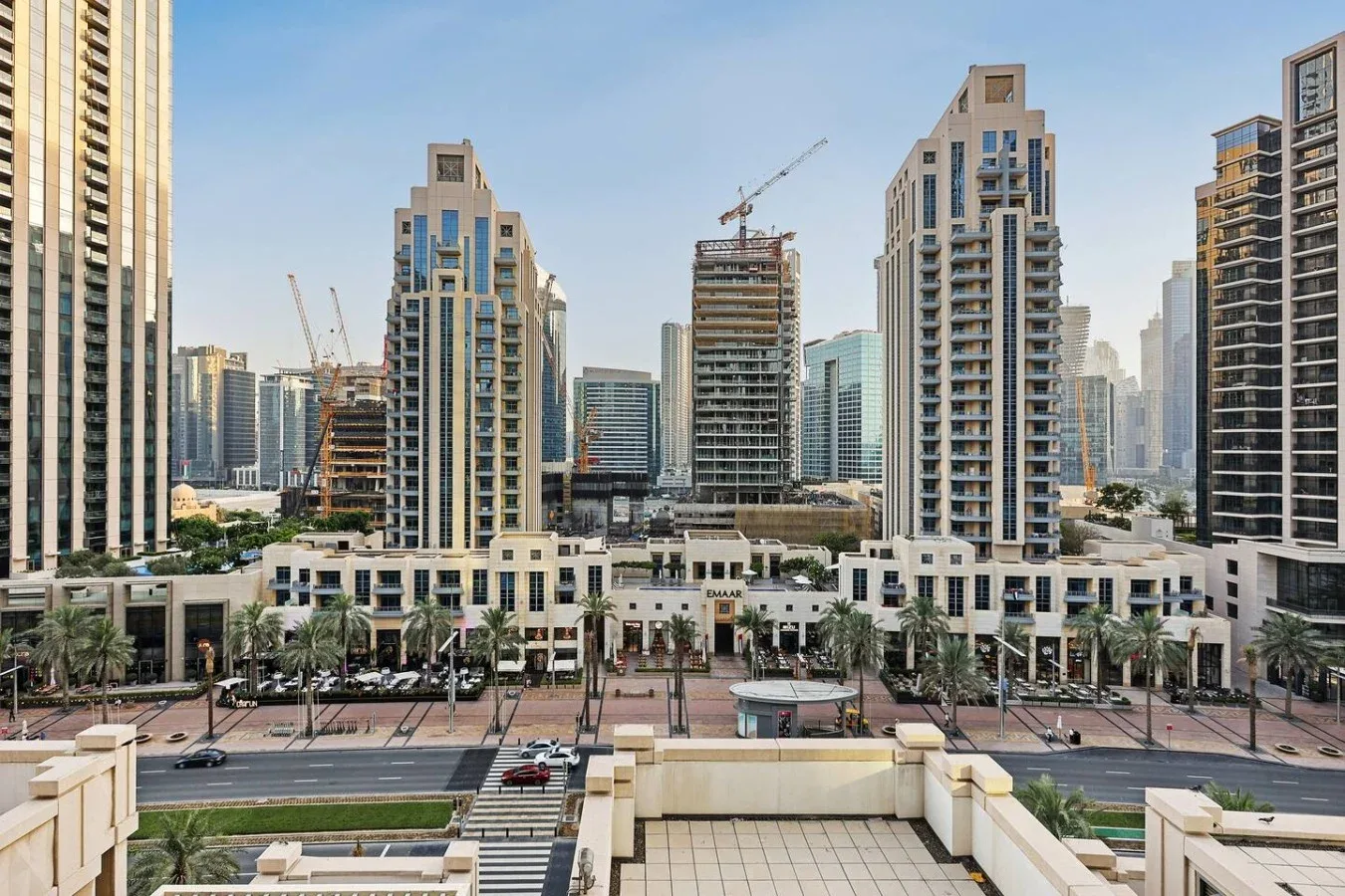 Un paisaje urbano de edificios modernos de gran altura, con grúas de construcción al fondo.