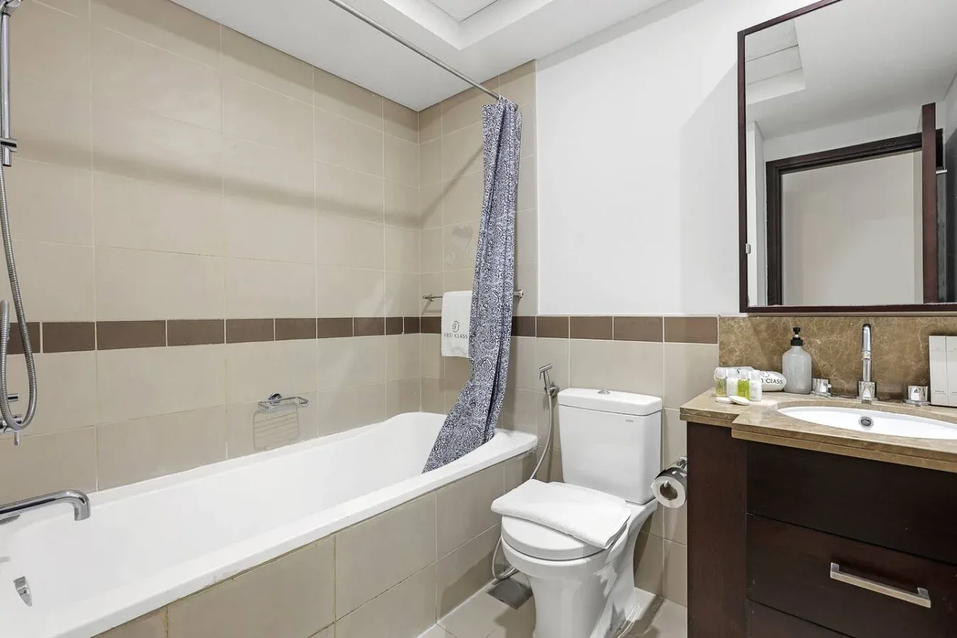 Un baño revestido de azulejos con bañera, inodoro y lavabo.