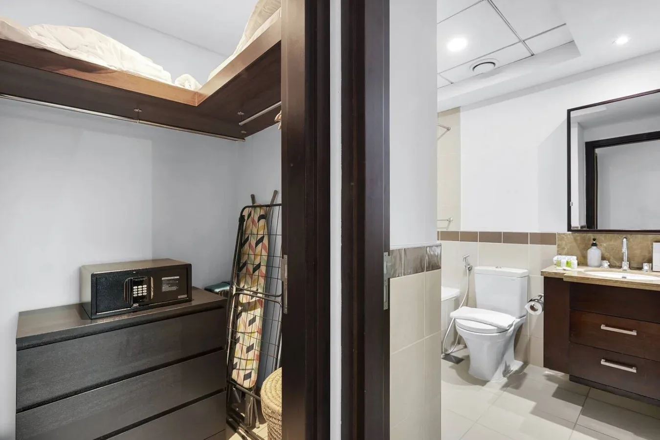 Un baño con inodoro y lavabo, y una cómoda oscura en primer plano.