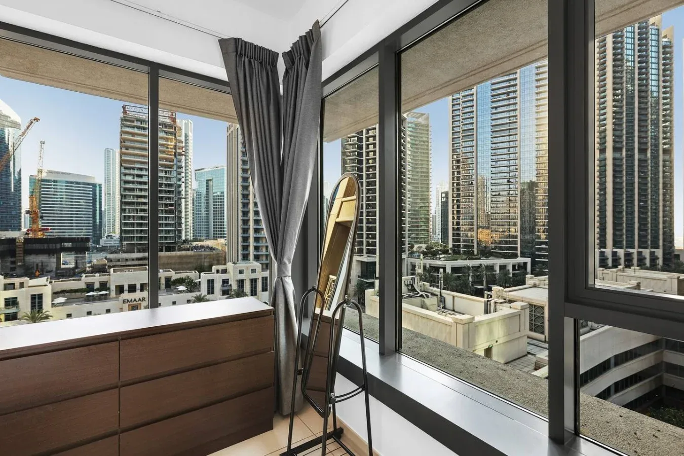 Una habitación con grandes ventanas que dan a un horizonte urbano y una cómoda de madera.