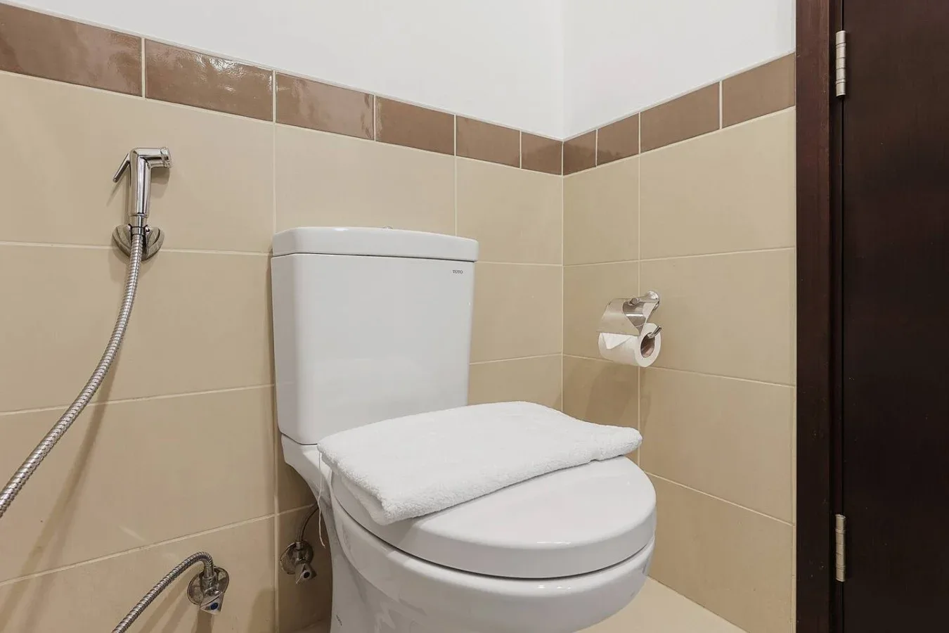 Un baño con azulejos, inodoro y ducha de mano.