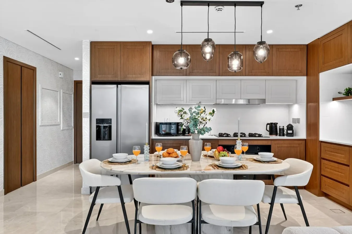 A bright kitchen and dining area features a long table set for a meal.