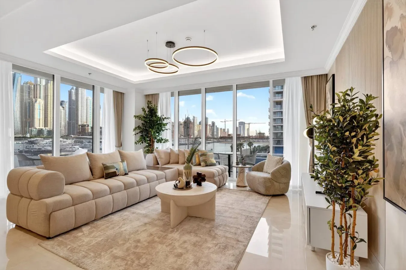 A bright living room with seating arranged around a coffee table and large windows.