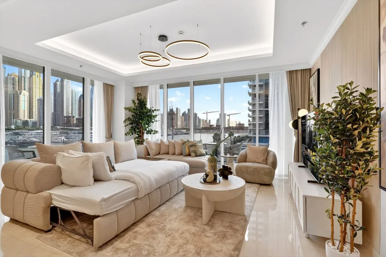 A bright living room with seating, a coffee table, and large windows overlooking city buildings.