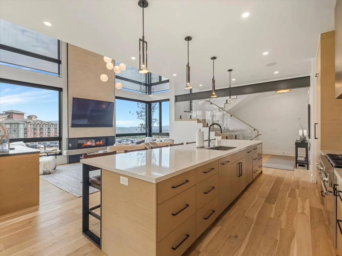 A modern kitchen with a large island, pendant lights, and tall windows.