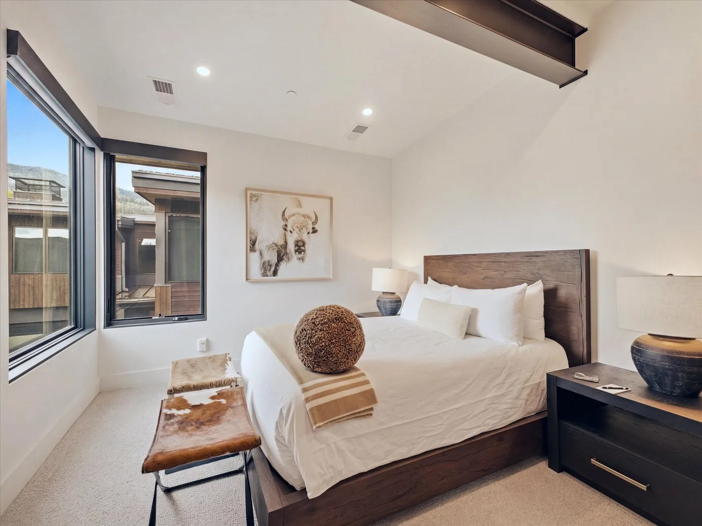A bright bedroom with a large bed and windows along one wall.