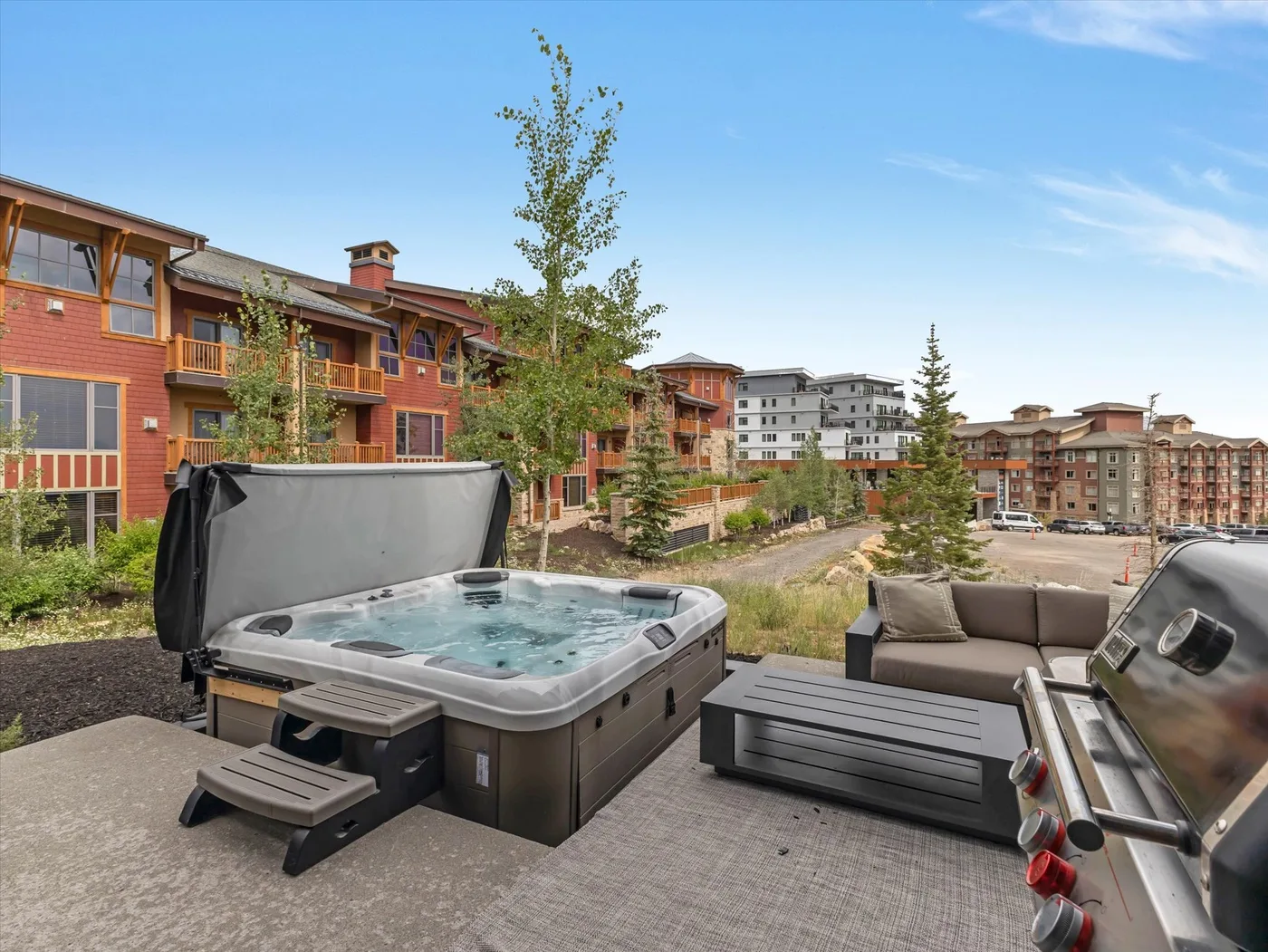 Un jacuzzi exterior y una zona de asientos dan a un complejo residencial ajardinado.